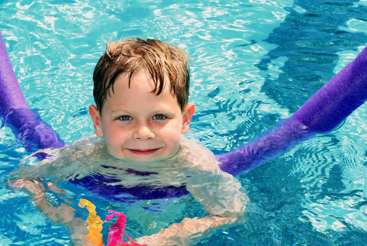 Child playing with pool noodle